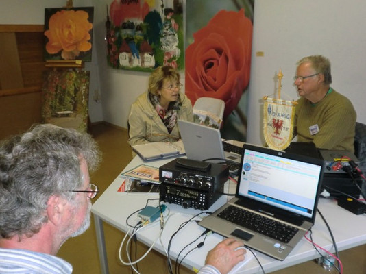 Bild - Frau Winkelmann vom Förderverein Ostdeutscher Rosengarten Forst (Lausitz) 1913 e.V. im Gespräch mit Diplommanager Wolfgang, DL9UJF. Im Vordergrund OM Peter, DG6ITP, an der Funkstation DL0FOR.